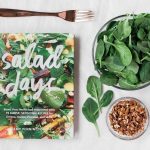 Salad day cookbook beside clear glass bowl with vegetable