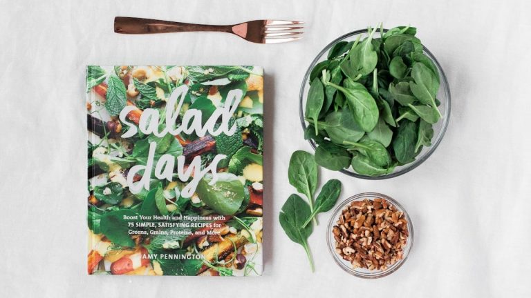 Salad day cookbook beside clear glass bowl with vegetable