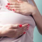 a woman with red nail polish holding her stomach