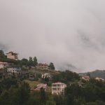 Houses nestled on a misty hillside.