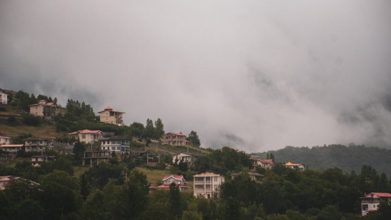 Houses nestled on a misty hillside.