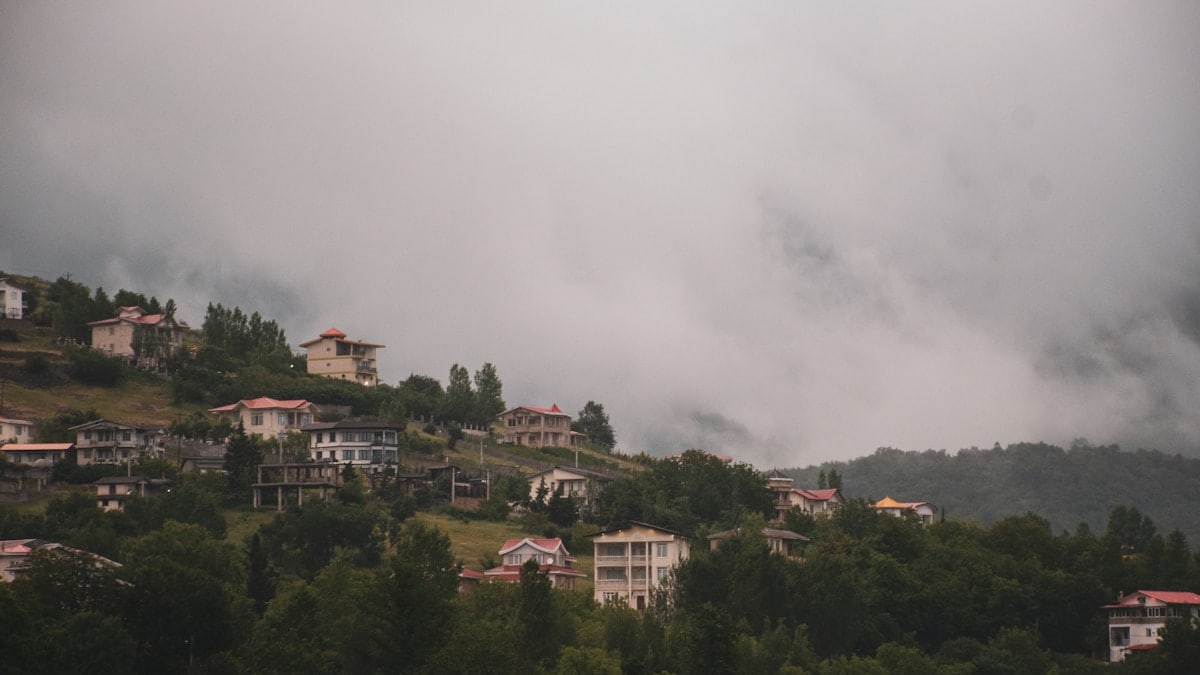 Houses nestled on a misty hillside.